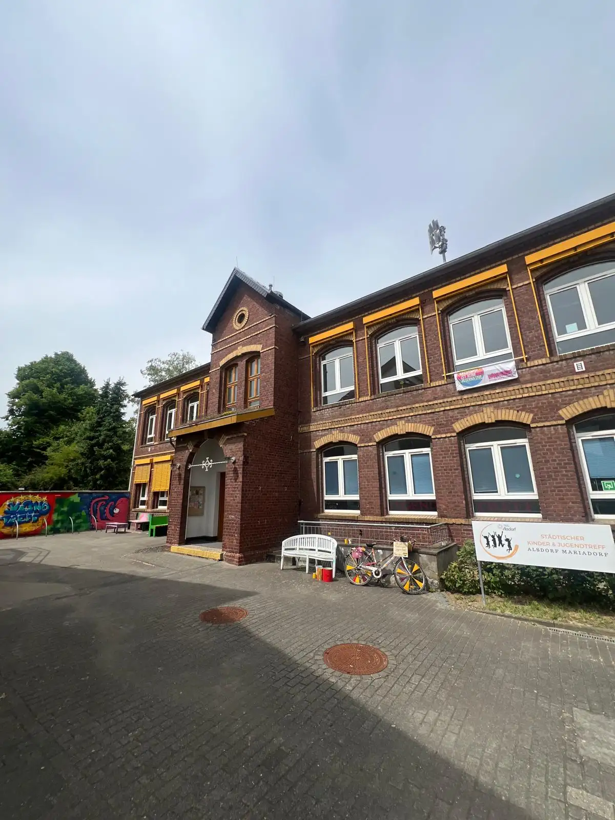 Ein Gruppenfoto im Jugendtreff mit Kindern und Jugendlichen vor einer Wand/mit Freizeit-Umgebung.