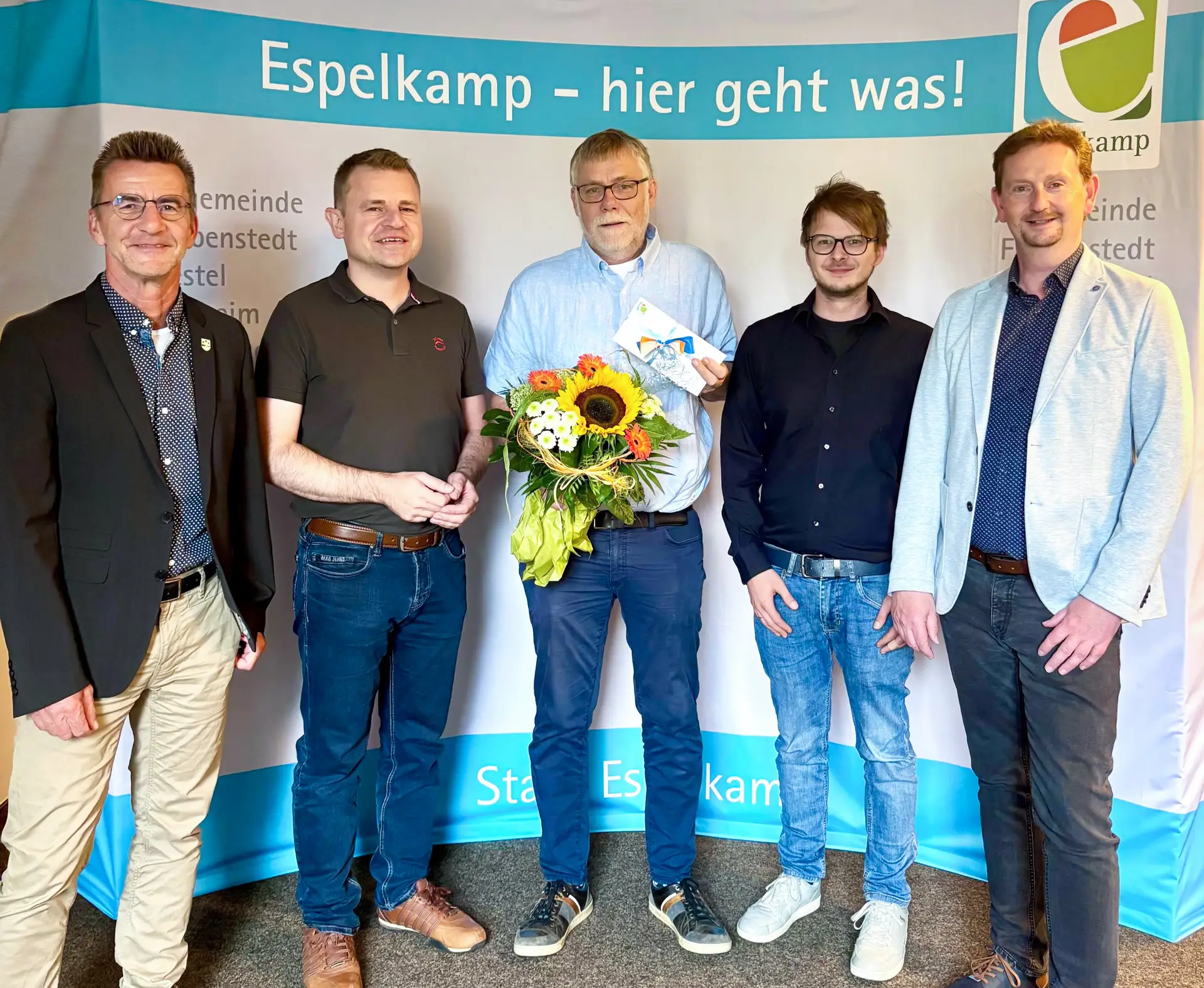 Vier Personen bei einer Verabschiedung: Andreas Bredenkötter, Matthias Tegeler, Daniel Sander und Björn Horstmeier überreichen Frank Engelhart ein Geschenk und Blumen.